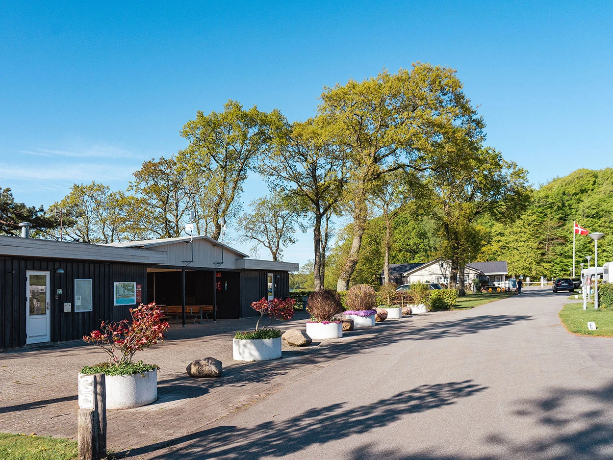 Rotes Küchengebäude aus Holz mit Blumenkübeln und einem Weg davor.