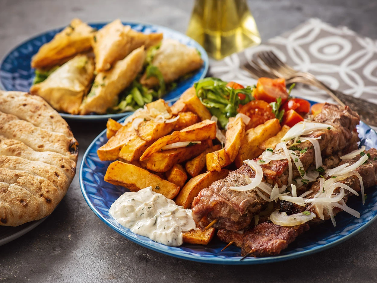 Griechisches Gericht bestehend aus Souvlaki, Pommes, Pita und Tsatsiki.