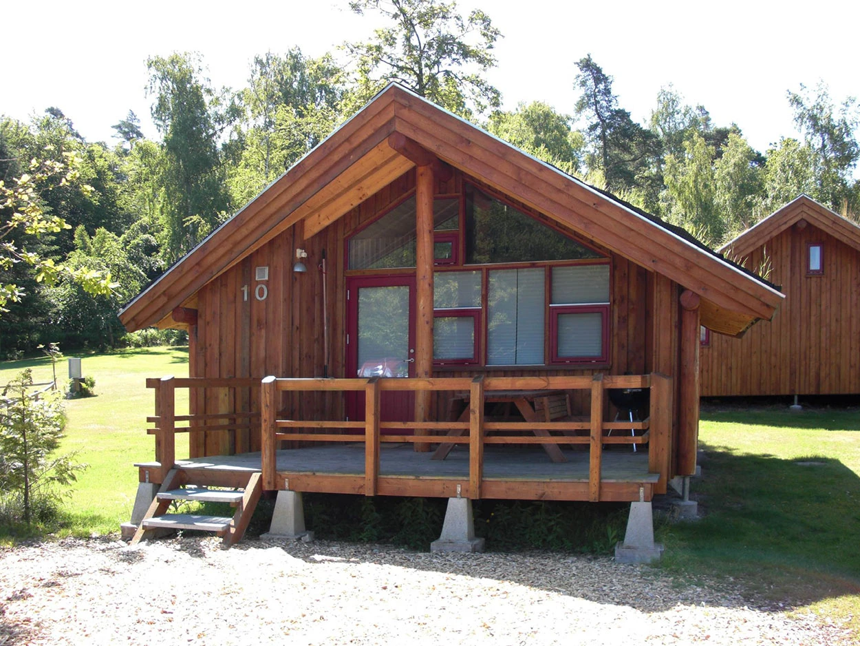 Frontansicht einer roten Holzhütte mit Veranda