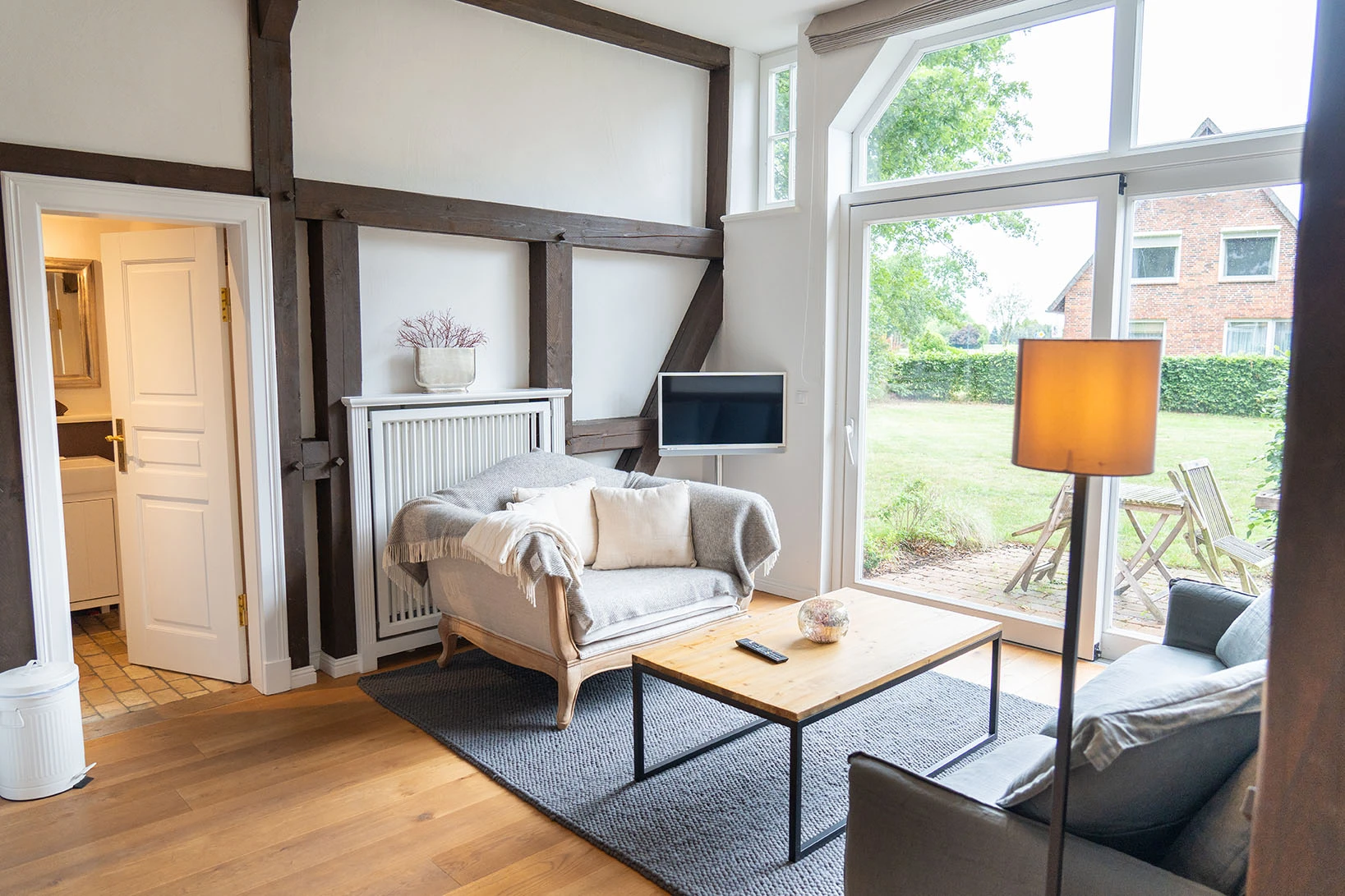 Coucharrangement mit Kaffeetisch und Fernseher im Wohnbereich vom Apartment 2 des Hofguts Bockelkathen mit Blick auf eine Terrasse.