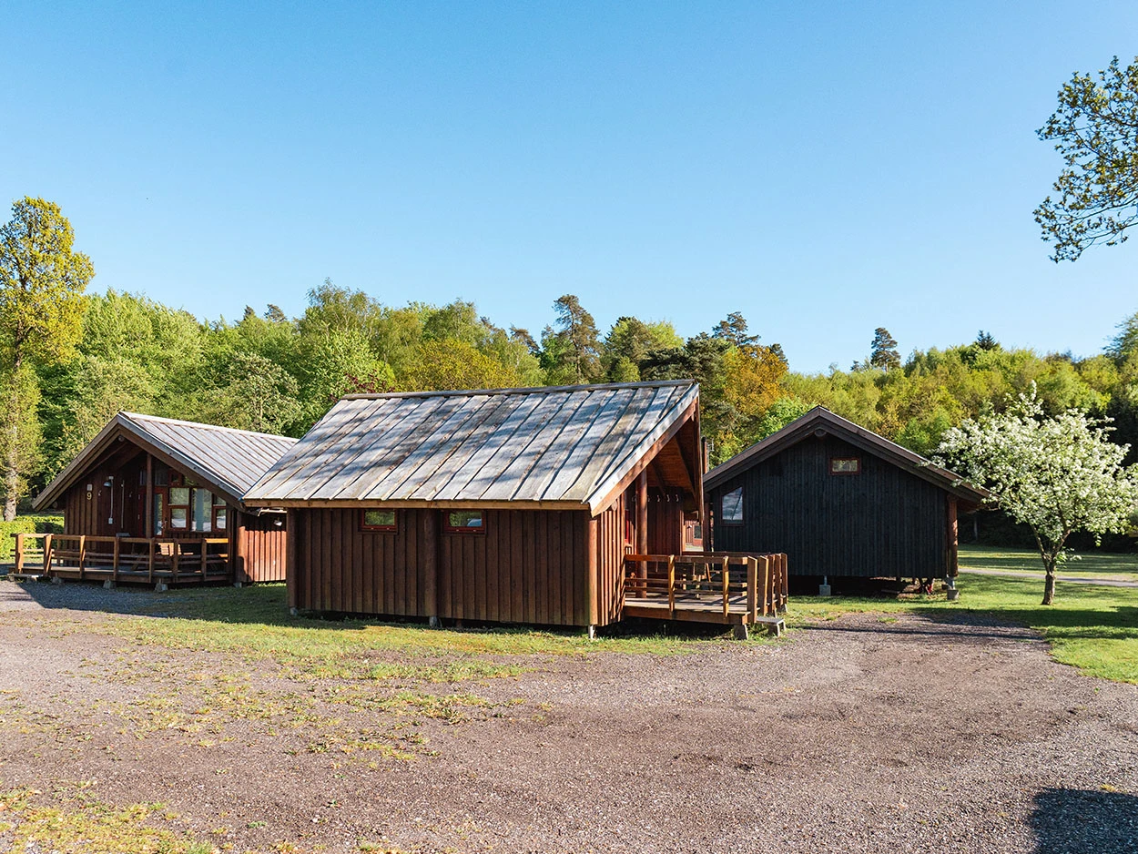 Drei rote Holzhütten auf einer Grasfläche