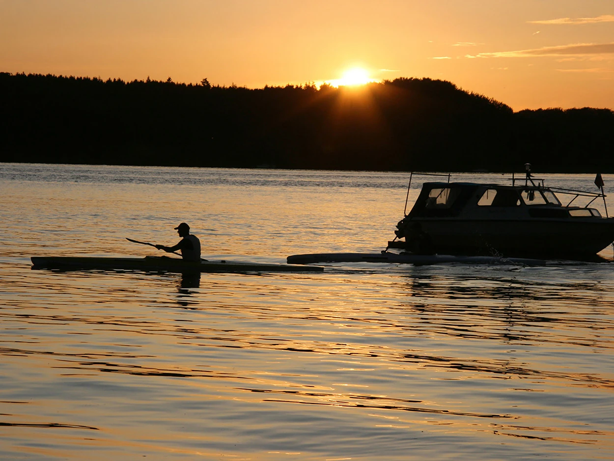 Ein noordwind-Gast paddelt mit seinem Kanu im Sonnenuntergang auf dem Wasser der Ostsee.