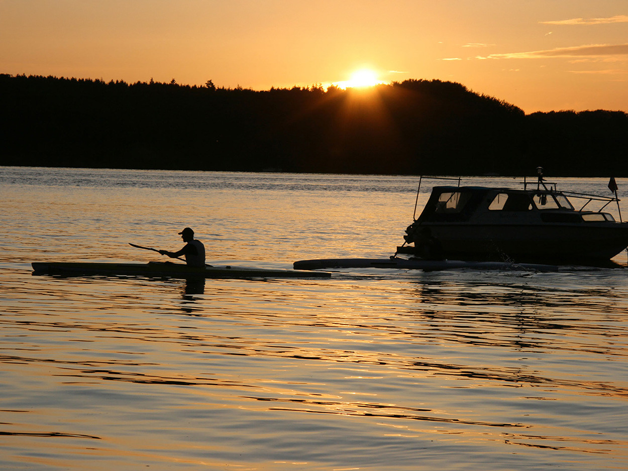Ein noordwind-Gast paddelt mit seinem Kanu im Sonnenuntergang auf dem Wasser der Ostsee.