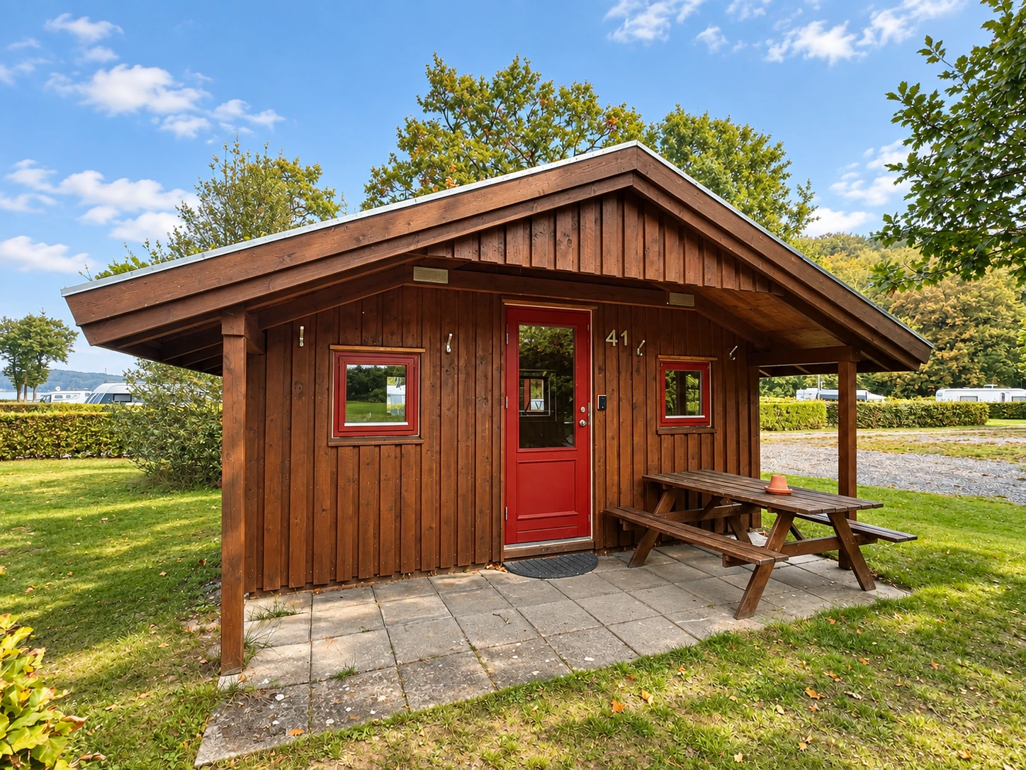 Cykelhytte – exterior Wooden Cykelhytte with red door and picnic table on the lawn